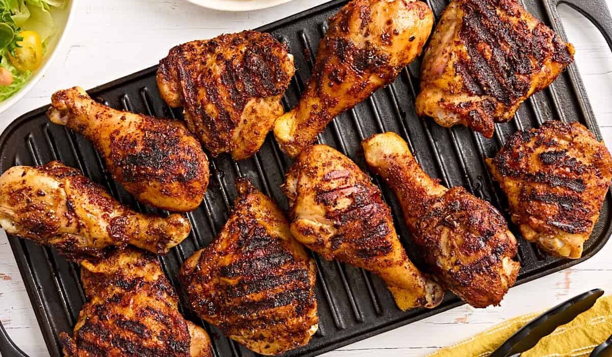 Dry rubbed grilled chicken drumsticks and thighs on a grill.