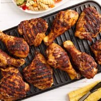 Dry rubbed grilled chicken drumsticks and thighs on a grill.