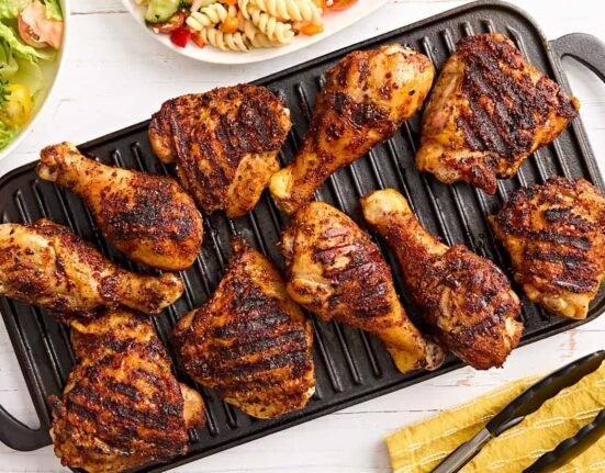 Dry rubbed grilled chicken drumsticks and thighs on a grill.