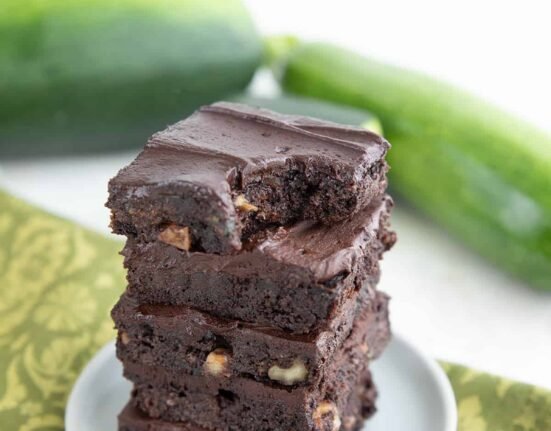 A stack of keto zucchini brownies with a bite taken out of the top one.